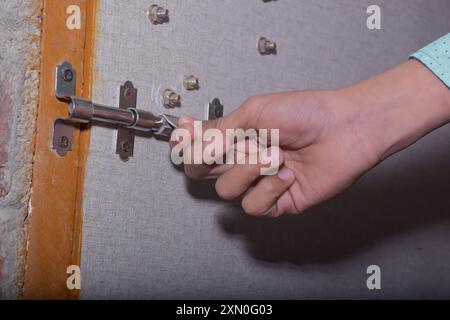 Hand of Asian teenage boy wearing light green shirt opens or closes latch Stock Photo