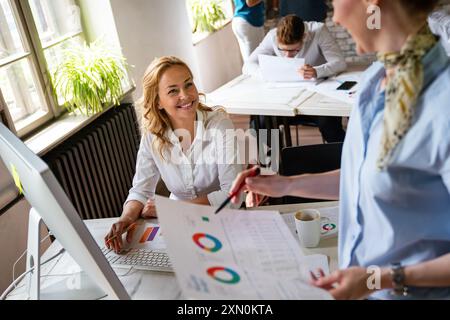 Group of young confident happy business people analyzing data during meeting in the office Stock Photo