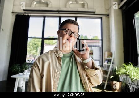 A young man with Down syndrome smiles while talking on the phone. Stock Photo
