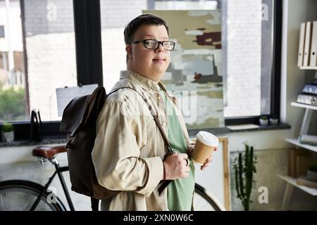 A young man with Down syndrome smiles while holding a cup of coffee. Stock Photo