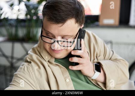 Young man with Down syndrome, glasses, brown shirt smiles while on phone Stock Photo