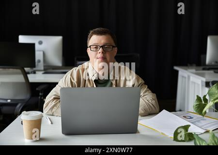 Young man with Down syndrome looks at camera while working on laptop Stock Photo