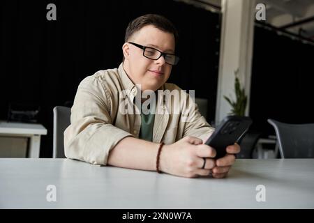A young man with Down syndrome smiles while using his phone. Stock Photo