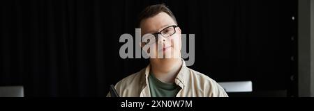 A young man with Down syndrome smiles at the camera. Stock Photo