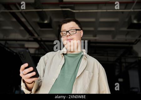 A man with Down syndrome smiles while holding his phone. Stock Photo
