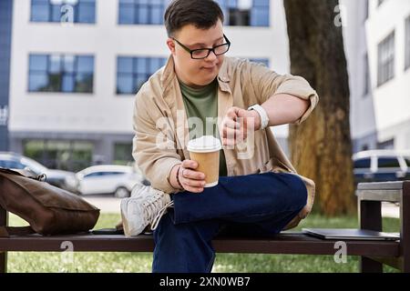 A man with Down syndrome checks his watch while holding a coffee cup. Stock Photo