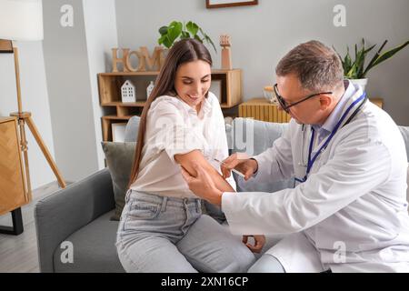 Young woman receiving vaccine from doctor at home Stock Photo