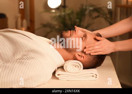 Handsome young man receiving facial massage in beauty salon Stock Photo