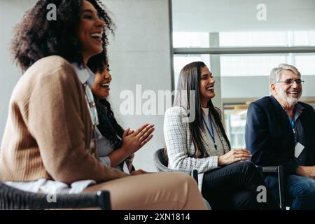 Diverse group of businesspeople networking and laughing during a corporate event, fostering connections and teamwork. Stock Photo