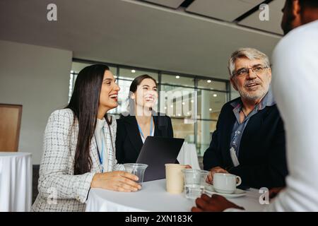 Group of coworkers chatting and networking at a conference table, discussing ideas and building professional relationships in a modern office. Stock Photo