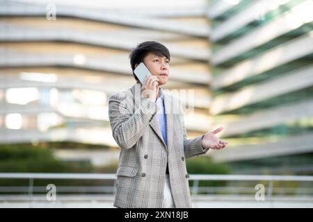 Man in Plaid Jacket Talking on Phone Outside Modern Building Stock Photo