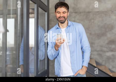 Smiling Man Using Smartphone by Glass Door Stock Photo