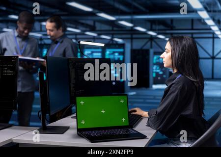 Computer scientist using green screen notebook to oversee blade servers used for managing databases. Woman working on mockup laptop in data center workspace storing information on rackmounts Stock Photo