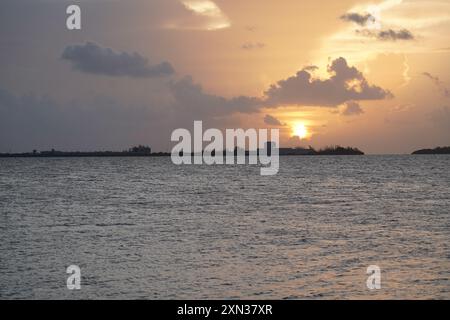 A mesmerizing golden sunset over a tranquil ocean, with distant islands creating a beautiful silhouette against the vibrant sky. The scene is perfect Stock Photo