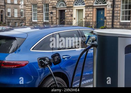 Edinburgh, Scotland, 07.17.2024: Blue electric car recharging its batteries on a street charging point in Edinburgh Stock Photo