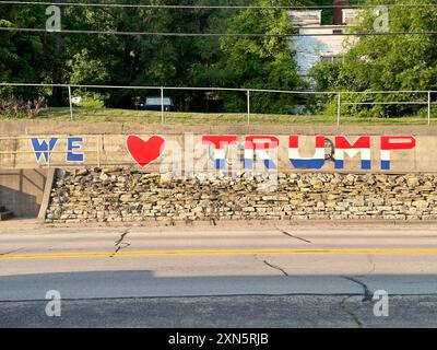 We Love Trump painted in red, white and blue on a cement wall by a highway outdoors. Stock Photo