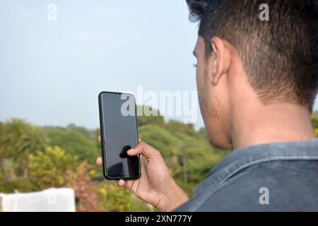 Online education, closeup of a schoolboy looking at mobile screen with outdoor background Stock Photo