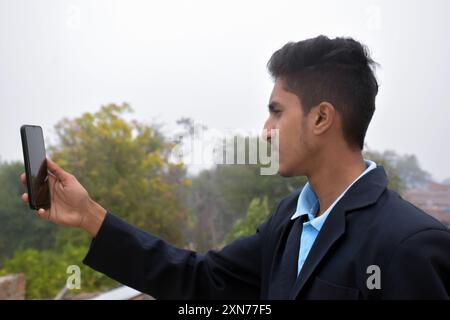 Online education, closeup of a schoolboy looking at mobile screen with outdoor background Stock Photo
