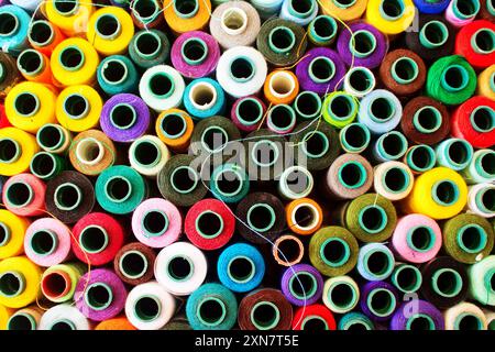 Top view of a vibrant collection of various colored thread spools. Multicolor sewing threads on reels. Colorful rolls of thread for sewing. Colorful a Stock Photo