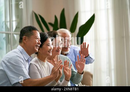 group of happy senior asian people two couple waving hands and greeting friends or family during video chat Stock Photo