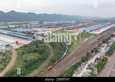 (240731) -- CHONGQING, July 31, 2024 (Xinhua) -- An aerial drone photo taken on July 30, 2024 shows a China-Europe freight train departing from the Tuanjiecun Station of Chongqing International Logistics Hub Park in Shapingba District of Chongqing, southwest China.  Chongqing International Logistics Hub Park, along with its 62 freight train routes, has risen to be a major hub of international freight trains in the country's western region.   As many international logistics channels converge in Chongqing, the mountainous city is leveraging its connectivity, playing a strategic fulcrum role and Stock Photo