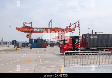 (240731) -- CHONGQING, July 31, 2024 (Xinhua) -- A vehicle transfers a container at the dry port of the New International Land-Sea Trade Corridor in the Chongqing International Logistics Hub Park in Shapingba District of Chongqing, southwest China, July 30, 2024. Chongqing International Logistics Hub Park, along with its 62 freight train routes, has risen to be a major hub of international freight trains in the country's western region. As many international logistics channels converge in Chongqing, the mountainous city is leveraging its connectivity, playing a strategic fulcrum role and tr Stock Photo