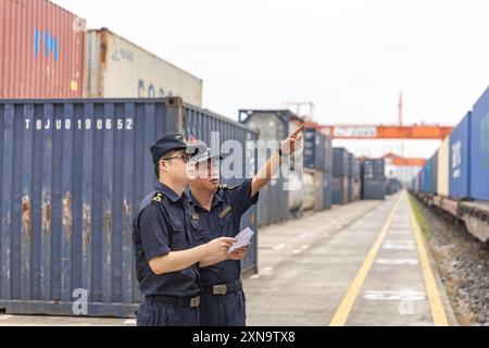 (240731) -- CHONGQING, July 31, 2024 (Xinhua) -- Customs staff inspect a China-Europe freight train at the Chongqing International Logistics Hub Park in Shapingba District of Chongqing, southwest China, July 30, 2024.  Chongqing International Logistics Hub Park, along with its 62 freight train routes, has risen to be a major hub of international freight trains in the country's western region.   As many international logistics channels converge in Chongqing, the mountainous city is leveraging its connectivity, playing a strategic fulcrum role and transforming into a crucial highland for opening Stock Photo