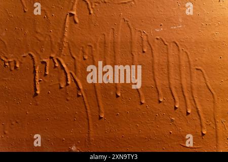 Orange painted surface. Paint texture with streaks on a concrete wall. Stock Photo