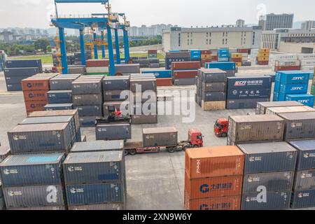 (240731) -- CHONGQING, July 31, 2024 (Xinhua) -- An aerial drone photo taken on July 30, 2024 shows a vehicle transferring containers at the dry port of the New International Land-Sea Trade Corridor in Chongqing International Logistics Hub Park in Shapingba District of Chongqing, southwest China. Chongqing International Logistics Hub Park, along with its 62 freight train routes, has risen to be a major hub of international freight trains in the country's western region. As many international logistics channels converge in Chongqing, the mountainous city is leveraging its connectivity, playi Stock Photo