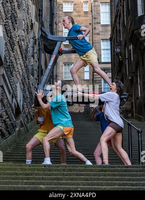 Edinburgh, Scotland, UK, 31 July 2024, Edinburgh Festival Fringe: Australian company Pony Cam make their Edinburgh Fringe debut with their show Burnout Paradise, multi-tasking on four treadmills.  The performers pose carrying treadmills up the Warriston’s Close staircase in the city’s Old Town. Credit: Sally Anderson/Alamy Live News Stock Photo