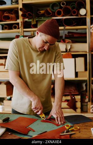 Male tailor using knife to cut leather fabric in old atelier Stock Photo