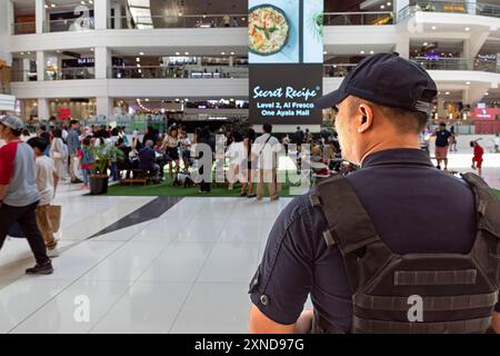 Philippino security guard watching over customers in Greenbelt shopping mall, Makati, Manila, Philippines Stock Photo