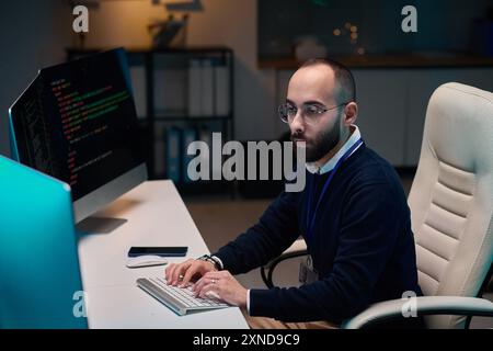 High angle portrait of bearded adult man using computer while coding while working late Stock Photo