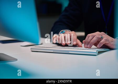 Minimal closeup of male hands typing on computer keyboard while working late in blue neon light copy space Stock Photo