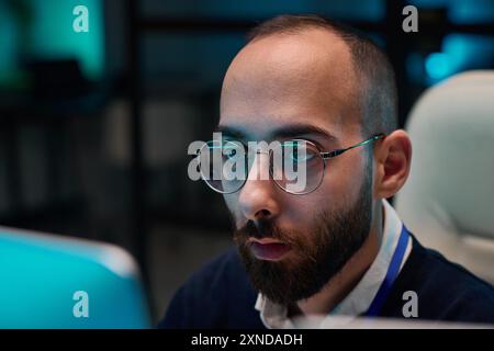 Minimal closeup of bearded adult man wearing glasses looking at computer screen while working late in blue light copy space Stock Photo