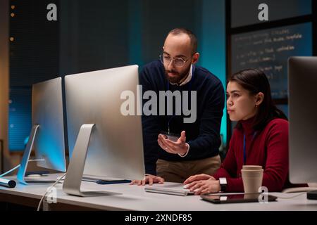 Minimal portrait of two people using computers while working in cybersecurity department with blue lights Stock Photo