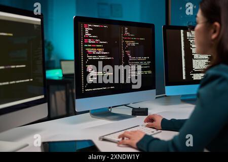 Computer with code lines on screen and unrecognizable young woman typing IT and cybersecurity concept copy space Stock Photo
