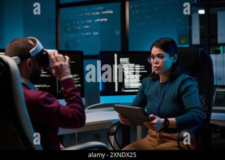 Portrait of young woman holding digital tablet while working on VR technology project with colleague Stock Photo