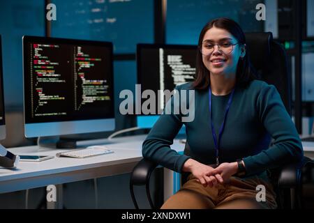 Portrait of smiling young woman wearing glasses as female computer programmer sitting at office workplace and looking at camera copy space Stock Photo