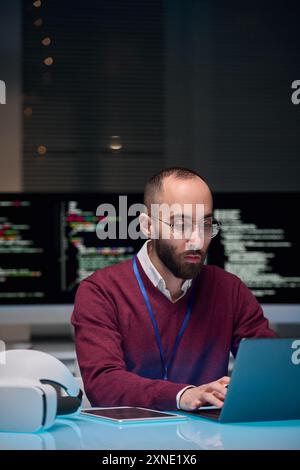 Vertical portrait of man wearing glasses and using computer at desk in IT development office Stock Photo