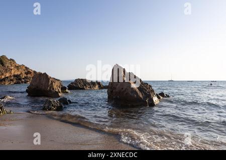 Rocky Shoreline with Gentle Waves at Sunset Stock Photo