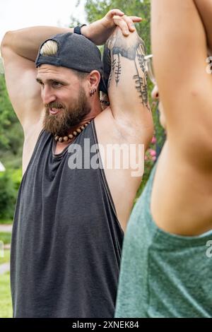 Athletes stretch their arms outdoors before starting their class. This routine reflects their focus on well-being and commitment to healthy living, en Stock Photo