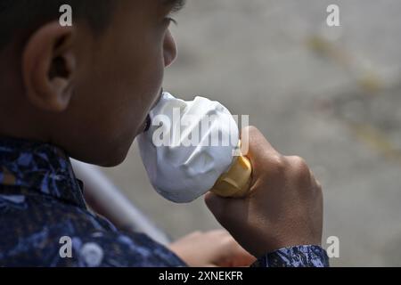 Young boy holding and eating a soft whip ice cream in cone, close up Stock Photo