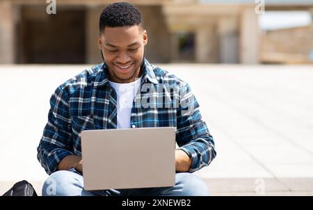 Black man using laptop, sitting in the city downtown Stock Photo