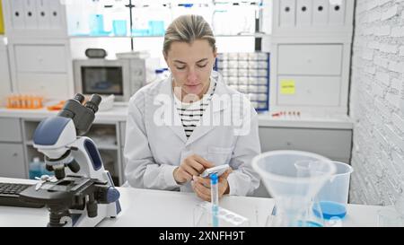 A focused caucasian woman scientist analyzes samples in a bright laboratory indoor setting. Stock Photo