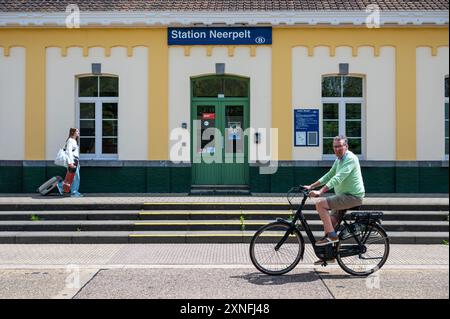 Neerpelt, Limburg, Belgium - July 10, 2024 - Colorful facade of the local railway station with an ebike driver and a teenage skater girl Stock Photo