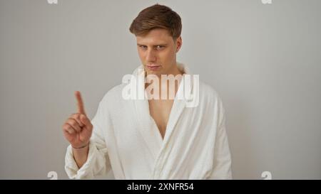 Handsome young man in a white bathrobe making a gesture on an isolated white background Stock Photo