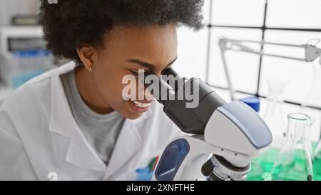 African american woman scientist using microscope in laboratory setting, portraying a professional research environment. Stock Photo