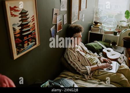 High angle shot of tired male student chilling on comfortable single bed while checking his social networks Stock Photo