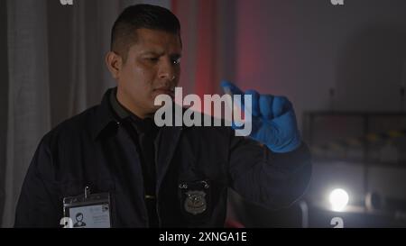 A focused hispanic detective man examines evidence at an indoor crime scene Stock Photo